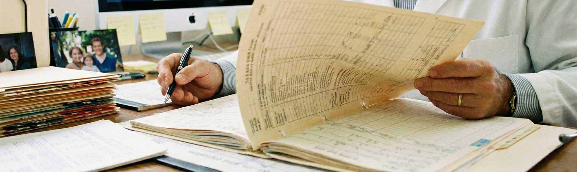 doctor1_banner Close-up of doctor sorting through pages of paperwork.